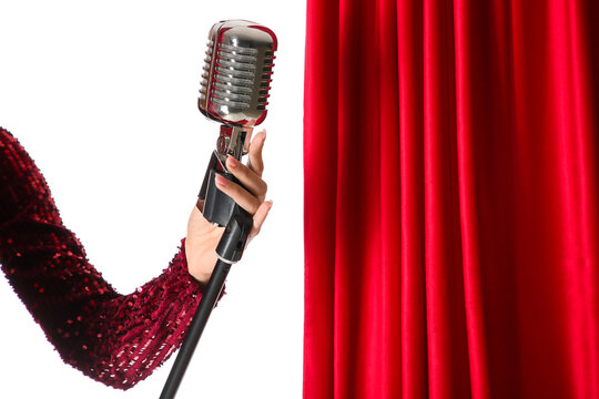 Female hand with microphone and red curtain on white background
