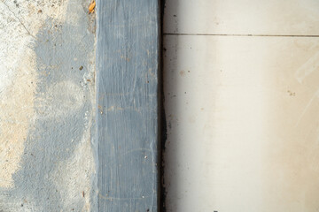 Top down view showing the boundary between rough concrete and smooth ceramic floor tiles. © BANG PELOG