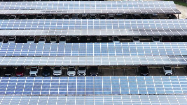 Close aerial approach to cars sheltered beneath solar panels