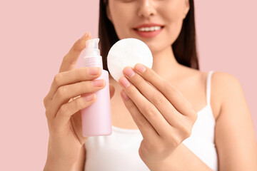 Young woman with cotton pad and micellar water for removing makeup on pink background, closeup © Pixel-Shot