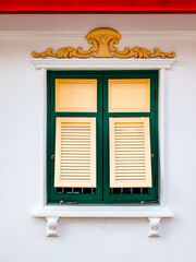 Traditional Thai window with green and gold shutters and carved ornament © Tavan