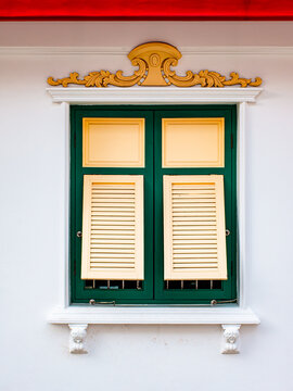 Traditional Thai window with green and gold shutters and carved ornament