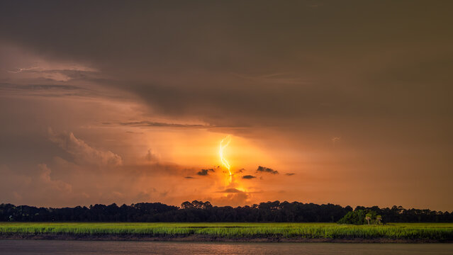 Lightning strikes above a landscape during a storm in the evening