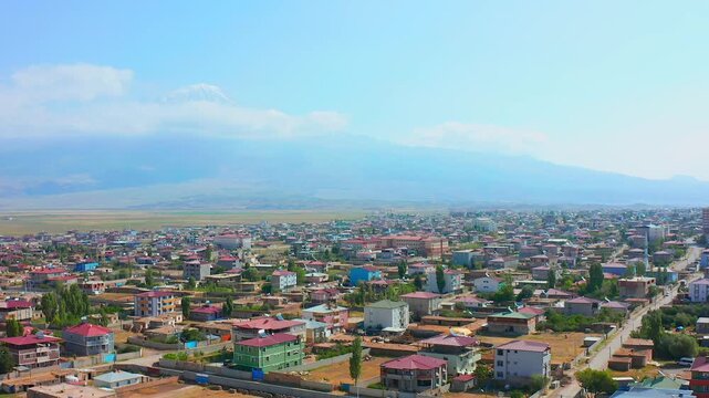 Drone hovers above Dogubayazit residential districts with Mount Ararat stretching across the skyline, supporting cityscape tourism, urban geography, destination marketing and eastern Turkey travel med