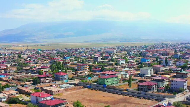 Drone hovers above colorful Dogubayazit neighborhoods beneath Mount Ararat, supporting destination promotion, urban geography, regional tourism, city planning context and eastern Turkey media.