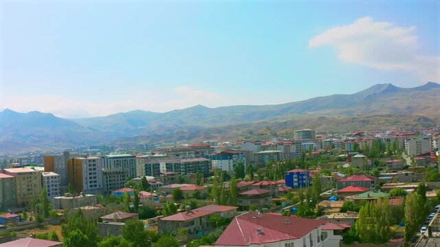 Drone descends above an eastern Turkish city, revealing residential blocks, open land and surrounding hills for urban development, regional geography, property, planning and tourism media.