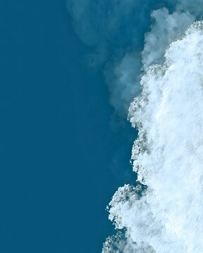 Aerial view of ocean wave foam meeting deep blue water surface