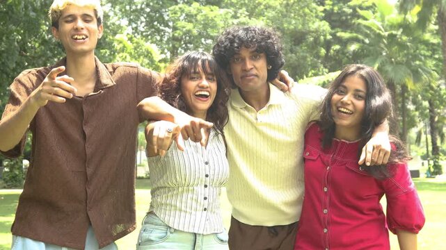 Group of diverse indian asian Gen z young adult friends laughing and embracing each other outdoors, sharing a happy moment and representing youth, unity, and friendship in a summer park.
