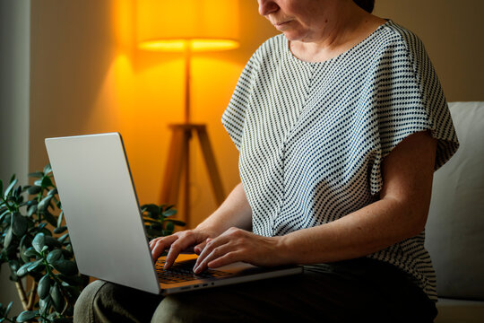 Woman working remotely on a laptop in a comfortable home environment. Home office, digital lifestyle and flexible work concept.