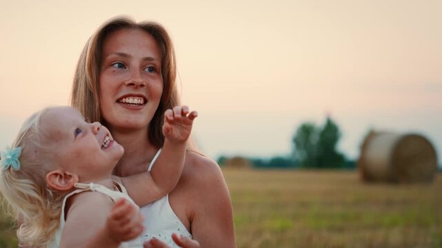Tender mother and toddler bonding in a peaceful countryside field at sunset, sharing affection, laughter, and playful gestures on a warm summer evening outdoors