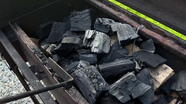 Stirring Charcoal Briquettes in Barbecue Grill with Long Metal Poker, Arranging Black Coals for Outdoor Fire and BBQ Cooking Preparation