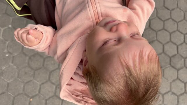 A playful baby in a pink sweatshirt being held upside down by his parent.