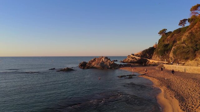 Aerial view taken from a drone of the coast of Lloret de Mar, Costa Brava, Spain, early in the morning at sunrise - the sea, beach and coastal cliffs of the city bay
