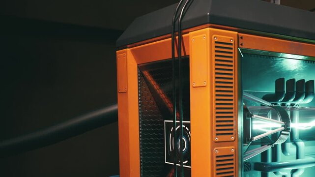 A computer case stands in a dim room. Bright lights shine from inside the case. Cables hang from the back, and several fans can be seen. The setup suggests a focus on technology and gaming.