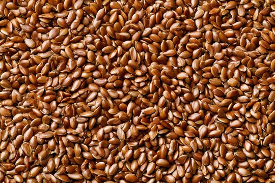 Brown flax seeds on a surface, showing texture and detail in close-up view