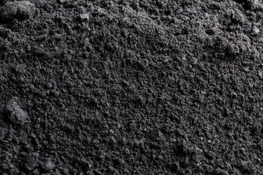 Black powder filling a space on a surface with fine texture and various particle sizes in daylight