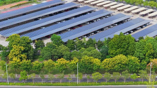 Lateral aerial view of a solar parking lot behind roadside trees
