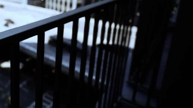 A balcony railing is visible with a view of the street below. The scene shows buildings and some sunlight. It appears to be daytime in a city environment.