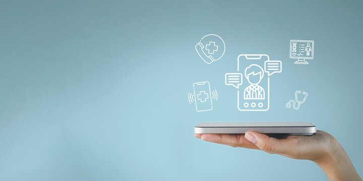 Telemedicine and digital healthcare concept. Hand holding a smartphone with medical icons overlay on a light blue background. Online doctor consultation, telehealth app, and health tech.
