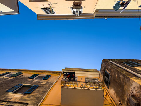 Weathered facades with green shutters and laundry in narrow Corfu Old Town alley, Greece