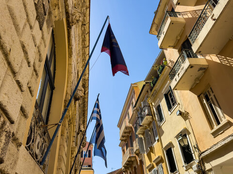 Greek flags above wrought-iron balconies in narrow alley, Corfu Old Town, Greece