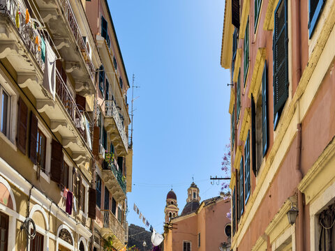 Sunlit narrow alley in Corfu old town, Corfu, Greece, pastel facades and church domes