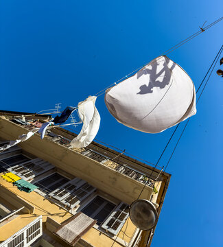White laundry hanging over narrow old town alley with shuttered buildings in Corfu, Greece