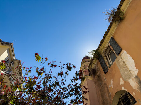 Weathered stucco facades and blue shutters, upward view in Corfu Old Town, Greece