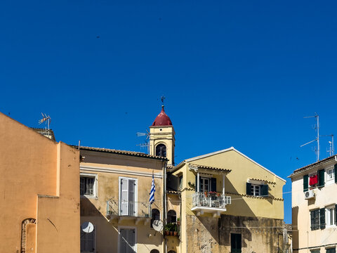 Red-domed bell tower, Greek flag, pastel buildings in Corfu Old Town, Corfu island, Greece