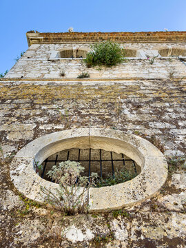 Low angle weathered stone wall with barred oval opening, New Fortress, Corfu Town, Greece