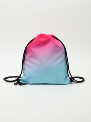 Vibrant gradient pink to blue drawstring backpack bag on a white background. © Radik