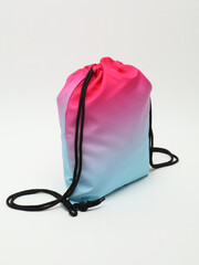 Vibrant gradient pink to blue drawstring backpack bag on a white background. © Radik