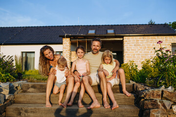 Happy young family spending summer evening together outside their new home.