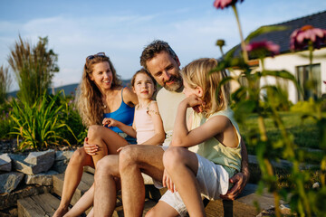 Happy young family spending summer evening together outside their new home.