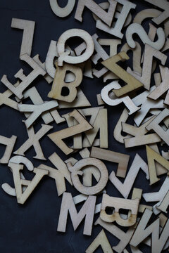 Abstract Wooden Letters and Numbers Scattered on Dark Background