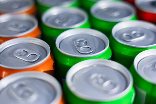 Aluminum can top green can orange can pull tab detail beverage packaging closeup texture metal lid silver rim pattern showing unopened drink container array