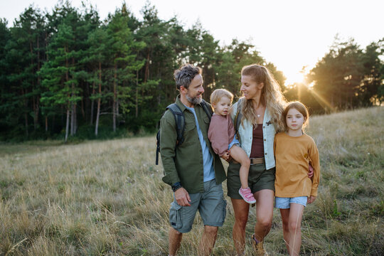 Family hiking together through countryside during summer camping trip.