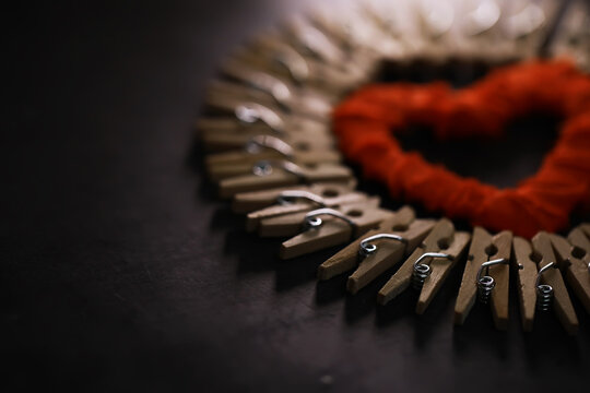 Heart-Shaped Design with Wooden Clothespins and Red Yarn on Dark Background