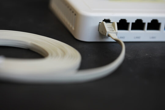 Close-Up of Network Router With Connected Cable on Dark Surface