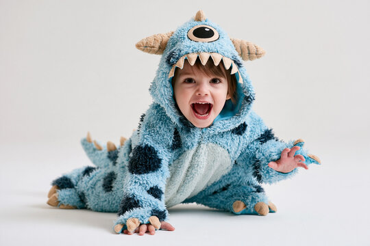 Monster Costume on White Background featuring happy child wearing blue furry cyclops outfit with horns teeth and claws