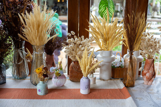 Dried flower arrangement wheat grass pampas bouquet ceramic vase sunlit window table display with neutral color rustic texture bohemian decor for cozy interior
