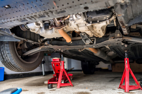 Car undercarriage elevated on jack stands during automotive maintenance