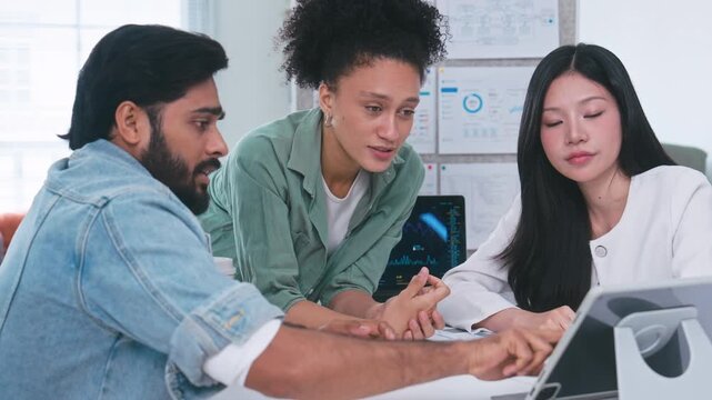 Three corporate professionals gathering around a digital tablet, looking seriously at the screen to solve a problem and discuss business strategy.