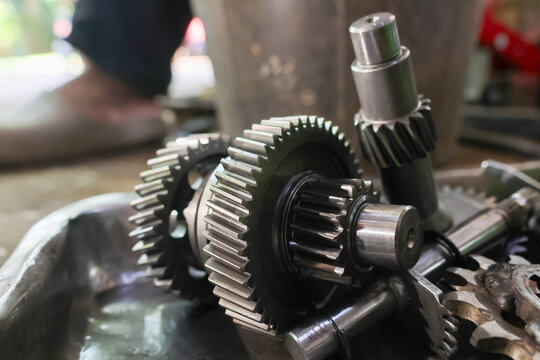 Mechanical gear assembly metal transmission component industrial repair workshop closeup of steel cogwheel, shaft, oil, and machinery part during maintenance