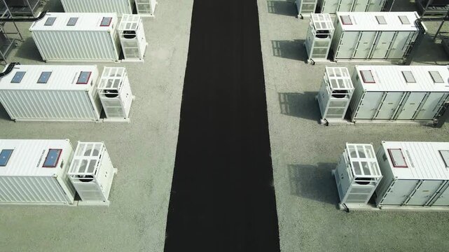Aerial view of a large scale BESS facility with rows of industrial containers, a crucial component for storing renewable energy and ensuring grid stability during peak consumption hours