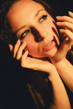 Cinematic, grainy close-up portrait of a young woman with wet skin and hair under dramatic moody lighting. Edgy alternative fashion and emotional concept.