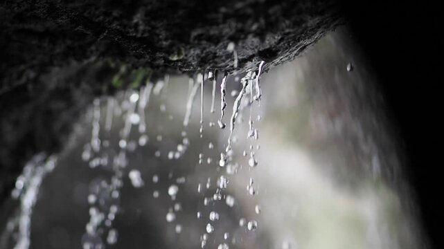 Water droplets falling from a rock surface