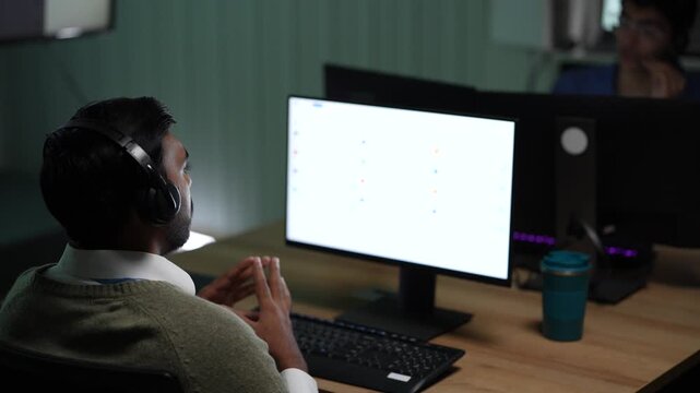 A planner reaching through a wall of notes slides a pink sticky into a new position and checks the sequence he has just changed inside a dark AI startup office.