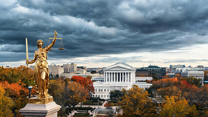 Obraz premium A golden Lady Justice statue overlooks neoclassical government buildings, framed by autumn trees under a stormy sky.