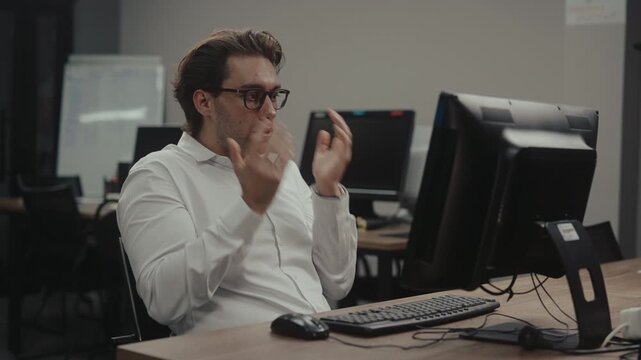 Stressed young businessman feeling overwhelmed by work at computer, struggles with problem, feels relief and satisfaction after finding solution in modern office. Shooting in slow motion.